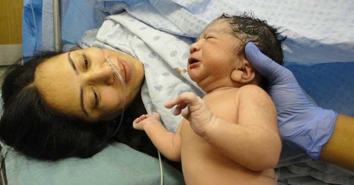 bác sĩ đang cho mẹ nhìn bé khi vừa sinh xong