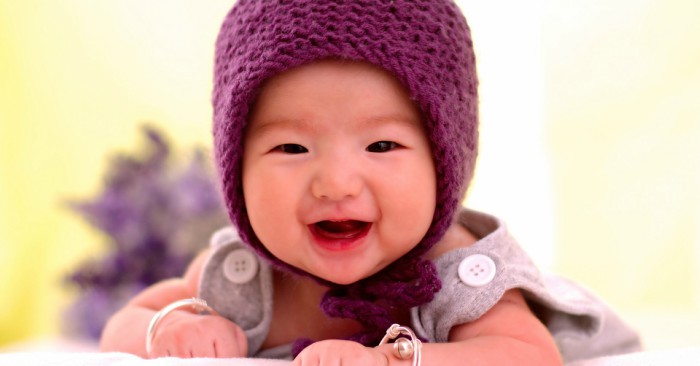 bé đội chiếc mũ len màu tím rạng rỡ nụ cười